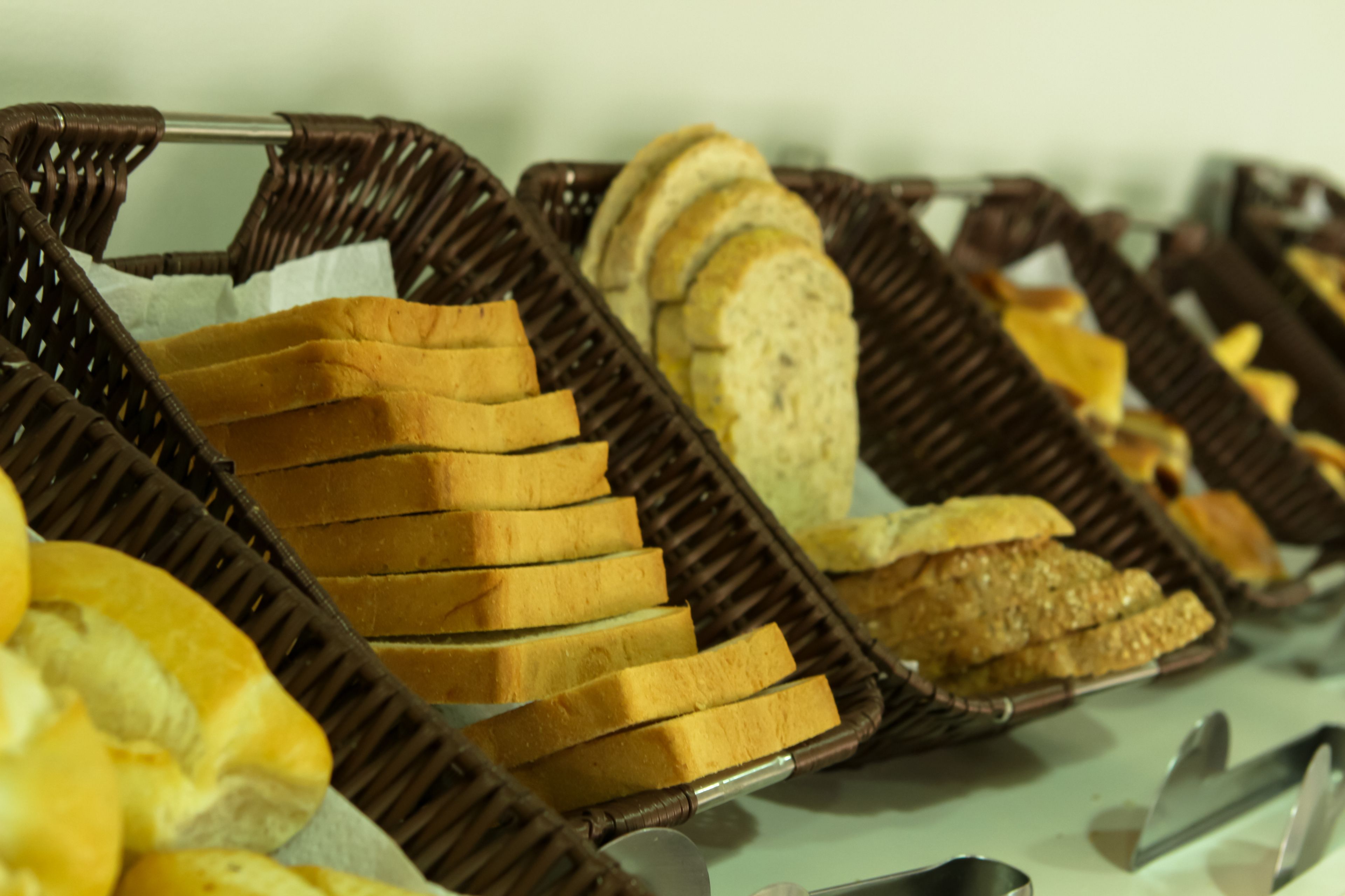 A buffet with various types of bread displayed in wicker baskets.
