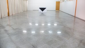 Una habitación amplia y vacía, con piso de baldosas y una mesa con mantel blanco y negro en el centro.