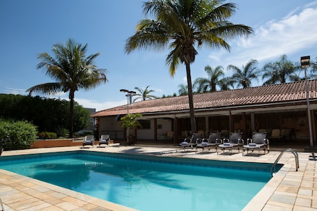 Una piscina al aire libre, sillones reclinables de piscina