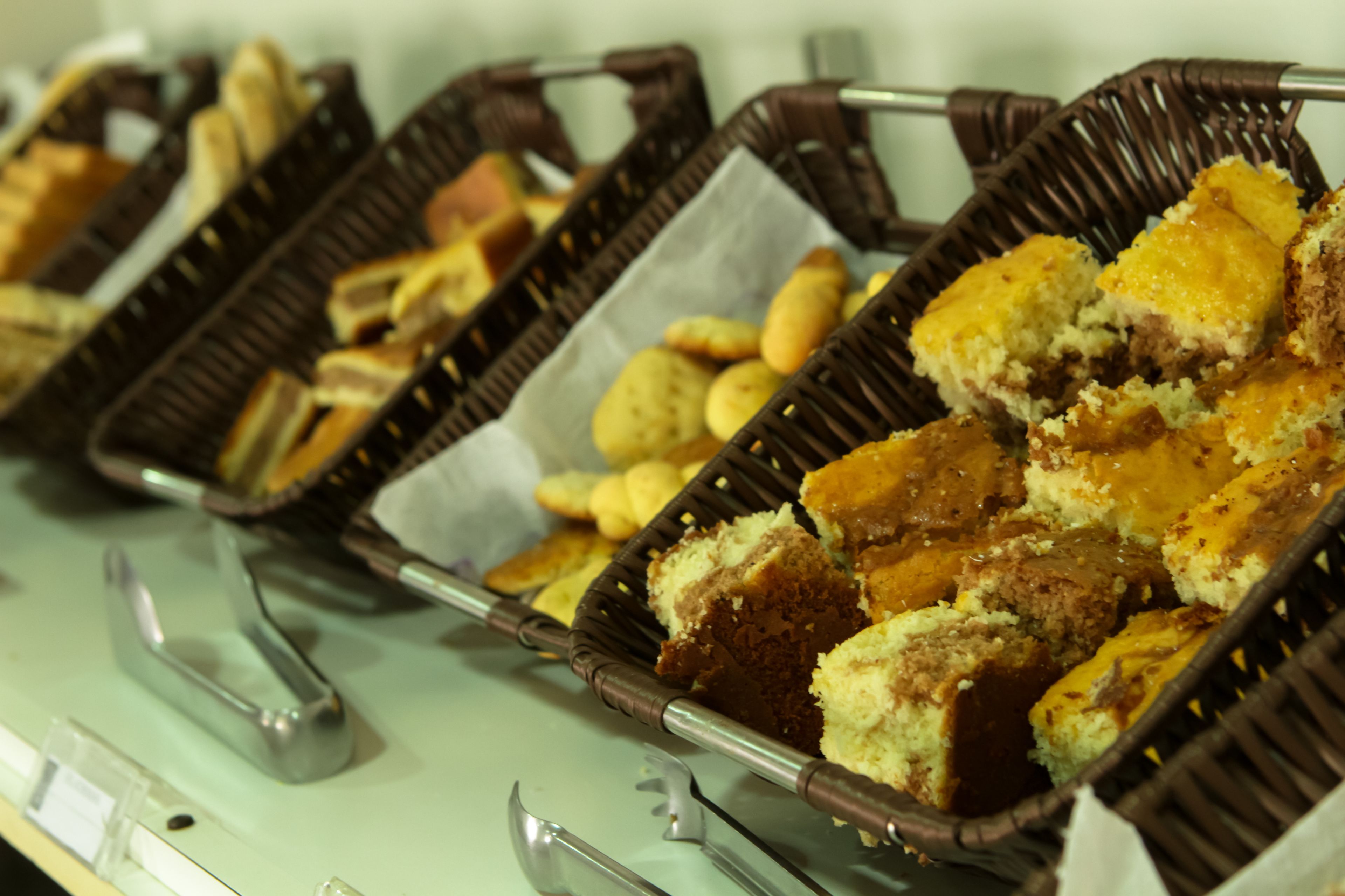 A buffet with various baked goods in wicker baskets.