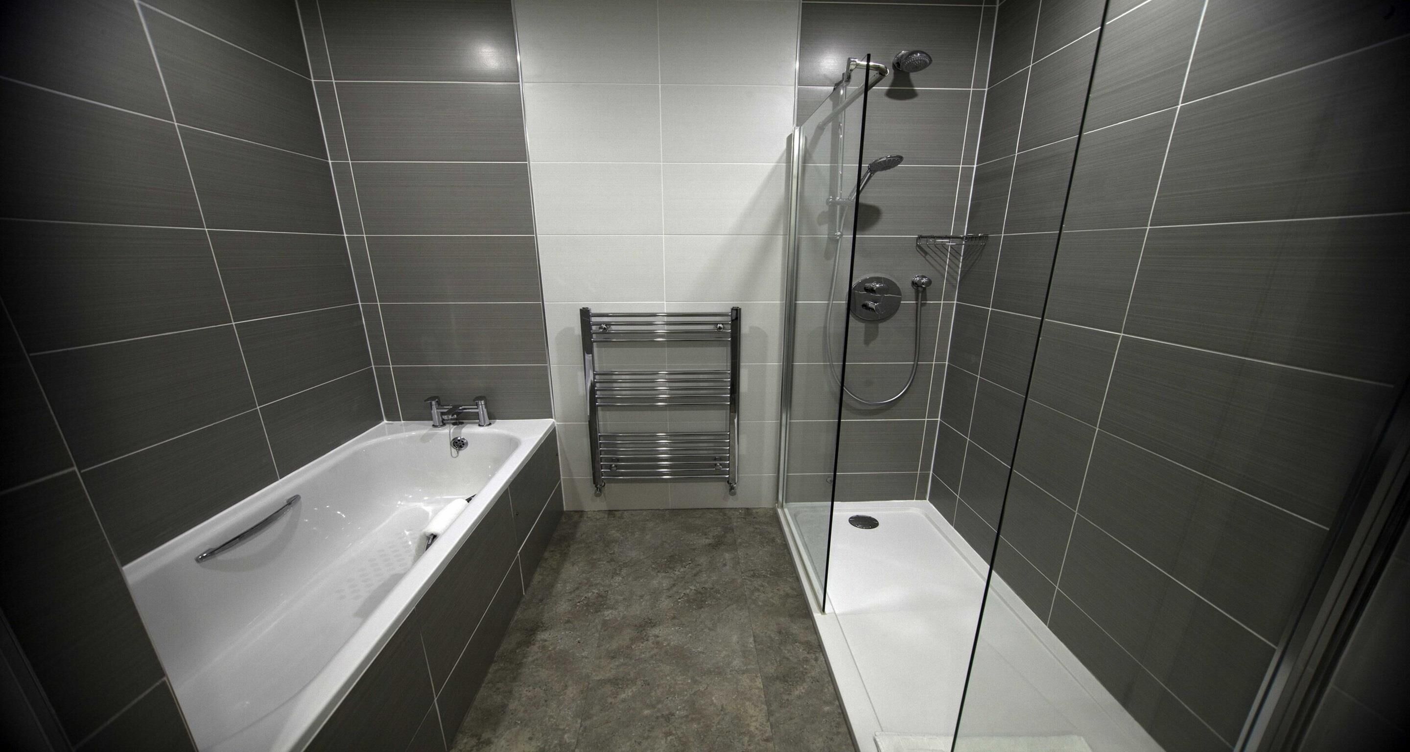 Un baño moderno con bañera, zona de ducha y cabina de ducha con paredes de vidrio.