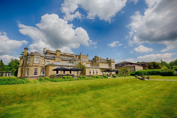 Stately building with a classical facade, surrounded by well-maintained lawns and mature trees.