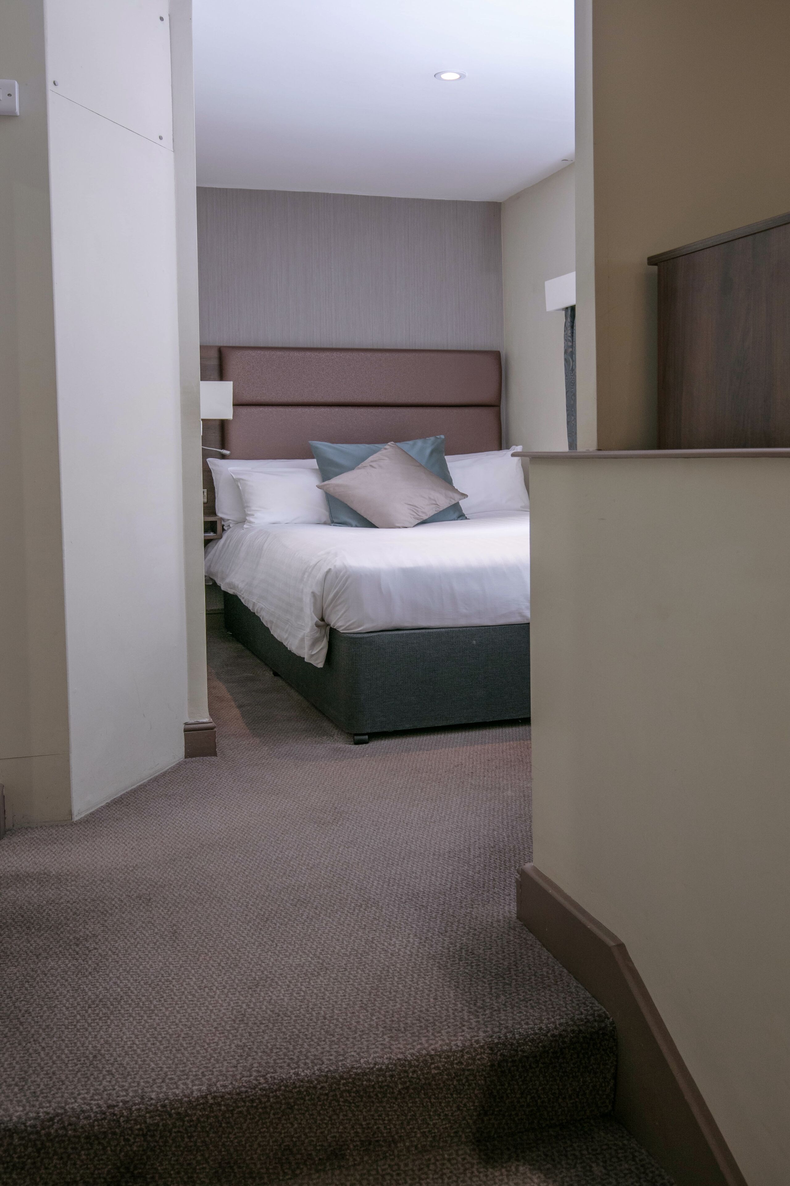 Ein Hotelzimmer mit einem Bett, einem Kopfteil und einem Teppichboden.