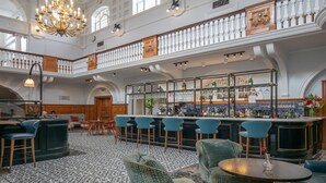 A spacious bar area with high ceilings, a chandelier, and a mezzanine level.