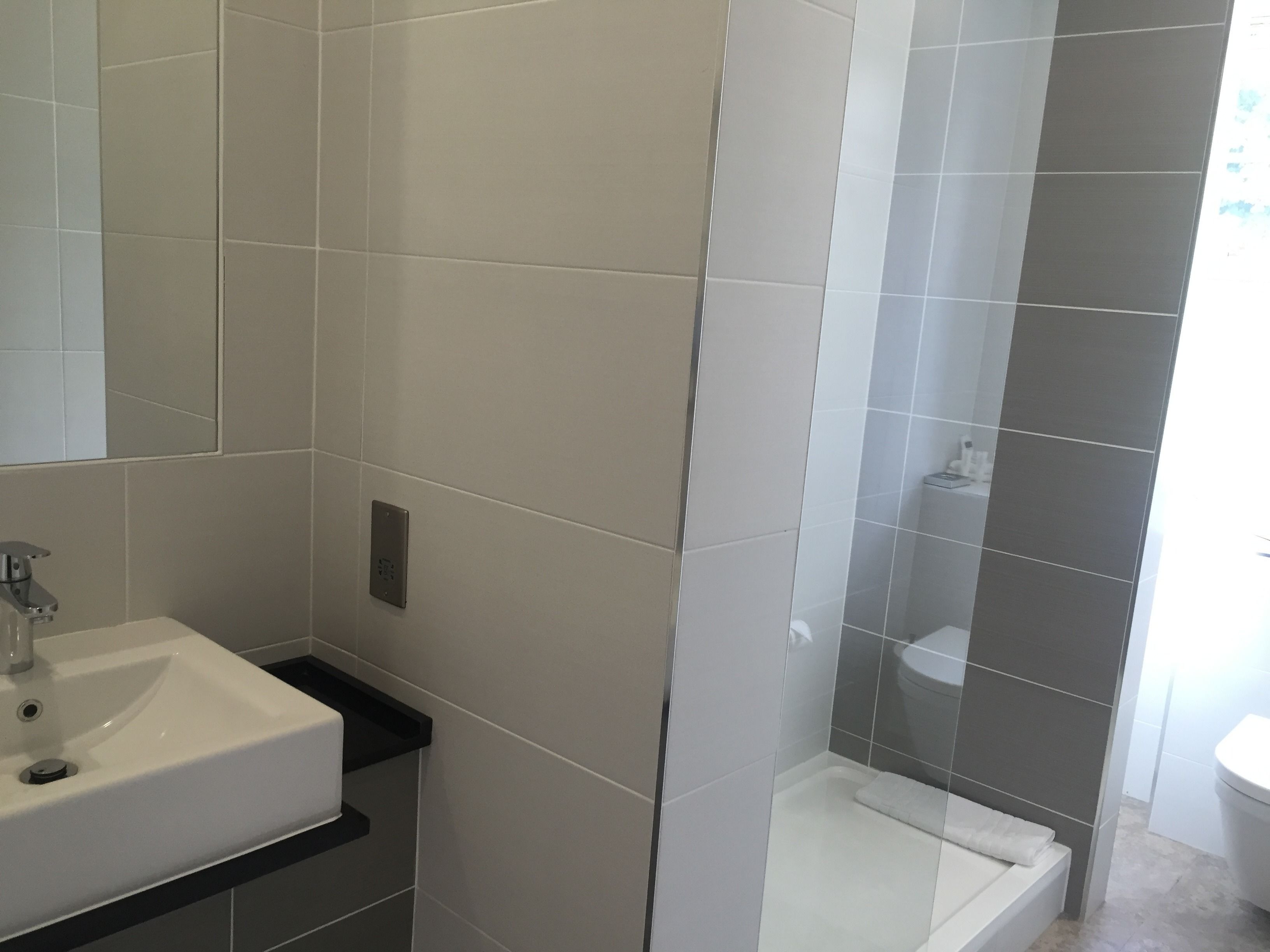 A bathroom with a white sink, a mirror, and a shower area.