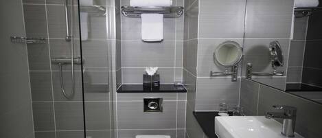 A modern bathroom with a glass-enclosed shower, a toilet, a sink, and a mirror.