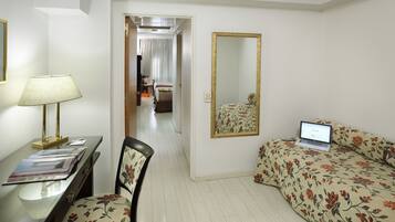 Quarto de hotel com escrivaninha, cadeira, cama e um laptop sobre a cama.