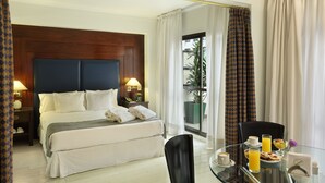 A hotel room with a large bed, a glass table with breakfast items, and a view of the outdoors. - Dolmen Hotel (Buenos Aires)
