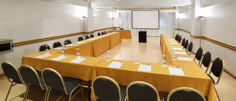 A conference room with a long table, chairs, a projector screen, and a whiteboard.