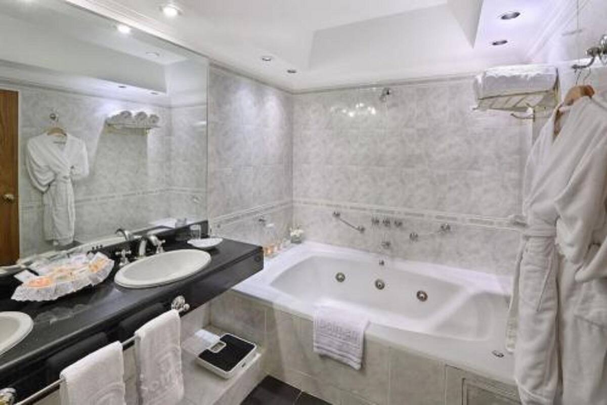 A modern bathroom with a large bathtub, two sinks, and a mirror.
