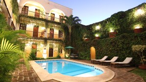 A courtyard with a swimming pool, lounge chairs, and potted plants. - La Misión de Fray Diego Boutique Hotel (Mérida)