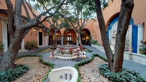 A courtyard with a fountain, trees, and a seating area. - La Misión de Fray Diego Boutique Hotel (Mérida)