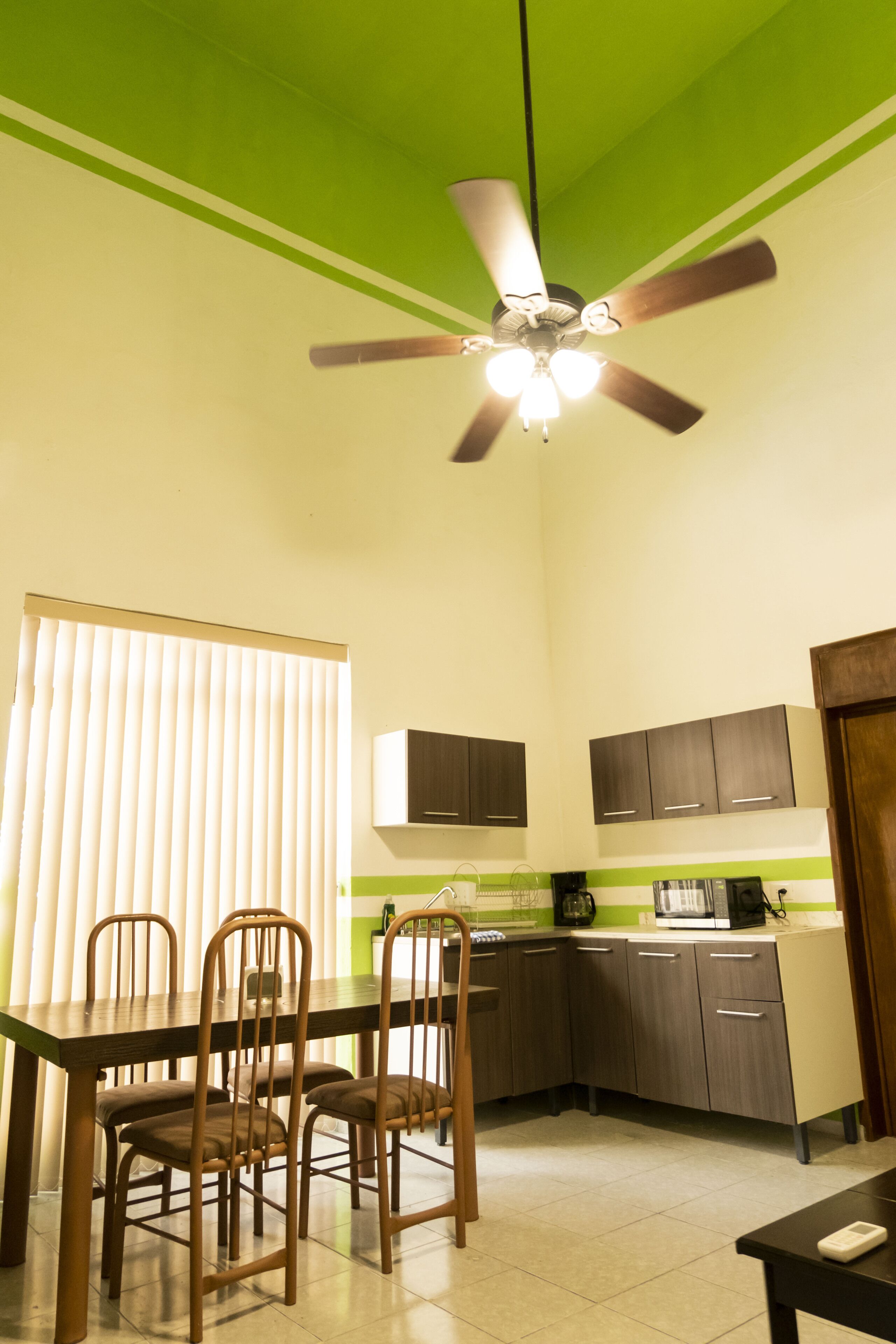 A kitchen with a dining area, including a table with chairs, a ceiling fan, and cabinets.