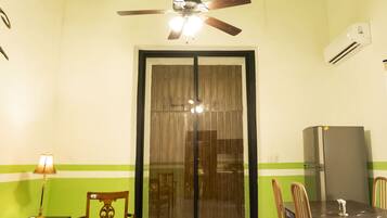 Un comedor con mesa, sillas, ventilador de techo y refrigerador.