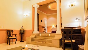 A hotel lobby with a reception desk, a staircase, and a seating area with a table and chairs. - La Misión de Fray Diego Boutique Hotel (Mérida)