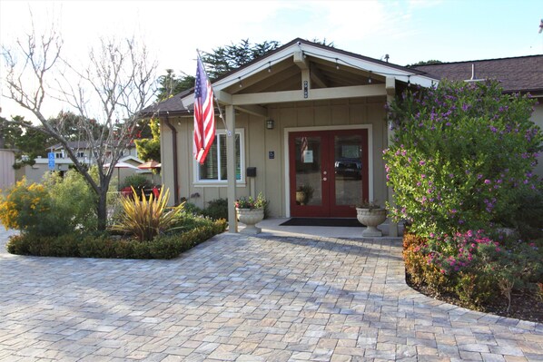 A building with a red door, an American flag, and a landscaped garden.