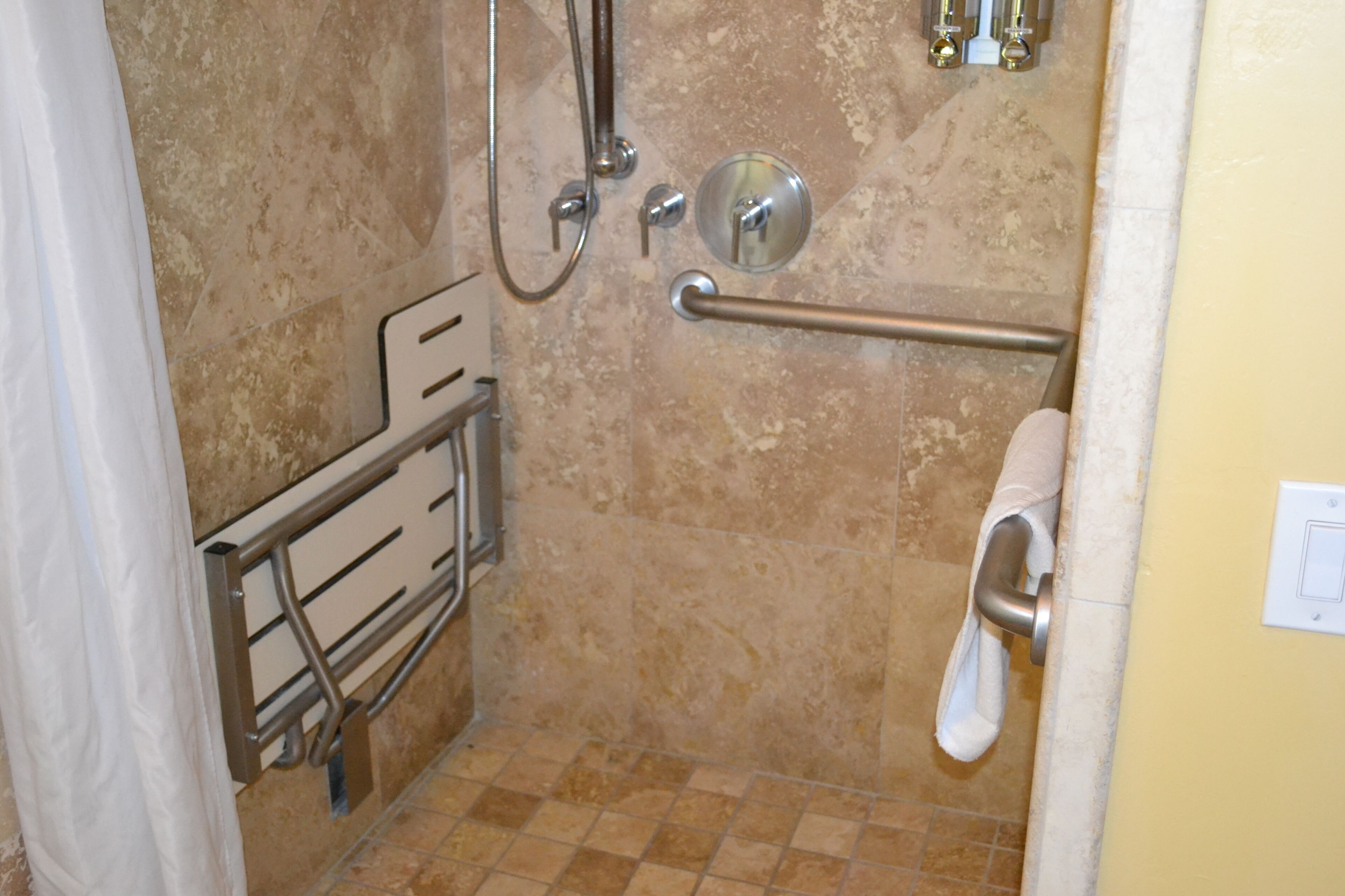 A bathroom with a shower, grab bars, a towel rack, and a toilet.