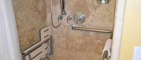 A bathroom with a shower, grab bars, a towel rack, and a toilet.