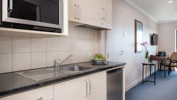 A modern kitchen with a built-in microwave, stainless steel sink, and a bowl of fruit on the counter.