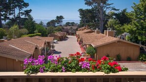 A row of wooden cabins with a clear view of the ocean in the background. - Sunset Inn (Pacific Grove)
