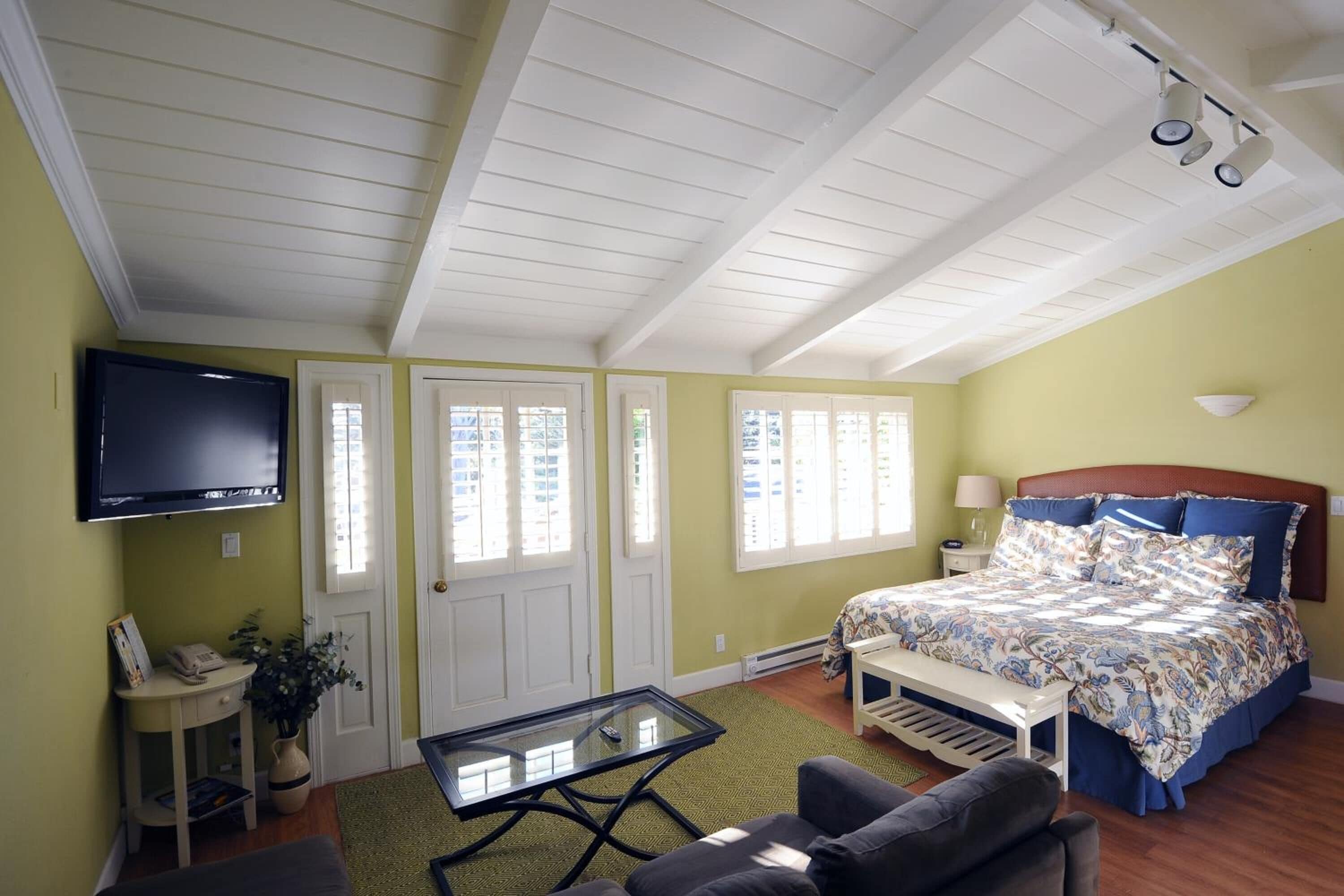 Un dormitorio con cama, televisión, escritorio y ventana.