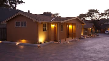 A residential building with a paved driveway and a well-lit entrance.