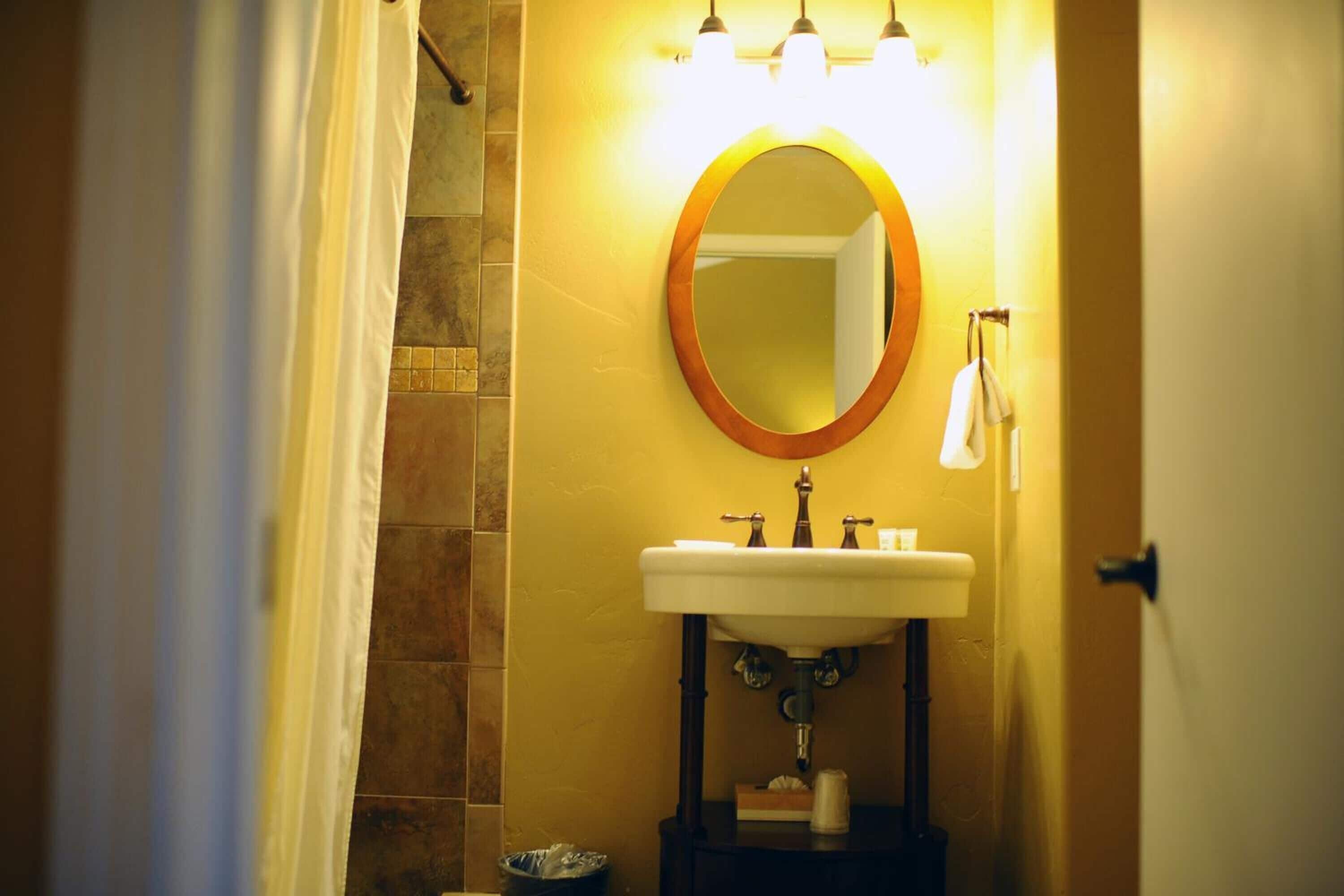 A bathroom with a sink, mirror, and shower.