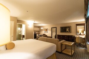 Ein Hotelzimmer mit einem großen Bett, einem Schreibtisch, einem Sessel, einer Couch, einem kleinen Tisch und einem Spiegel.