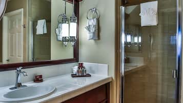 Une salle de bain moderne avec un grand miroir, deux lavabos, un meuble-lavabo et une douche à parois de verre.