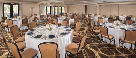 A large banquet hall with round tables set for dining, arranged in rows.