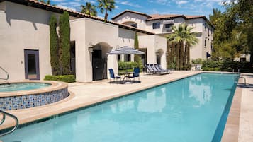 A swimming pool with lounge chairs and a covered seating area.