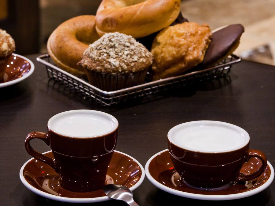 A table with two cups of coffee, a donut, and a muffin.