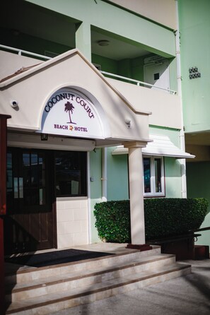 A two-story building with a sign reading "Coconut Court Beach Hotel".