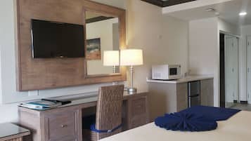 Una habitación de hotel con una cama, un escritorio con lámpara, un televisor, un microondas y un armario.