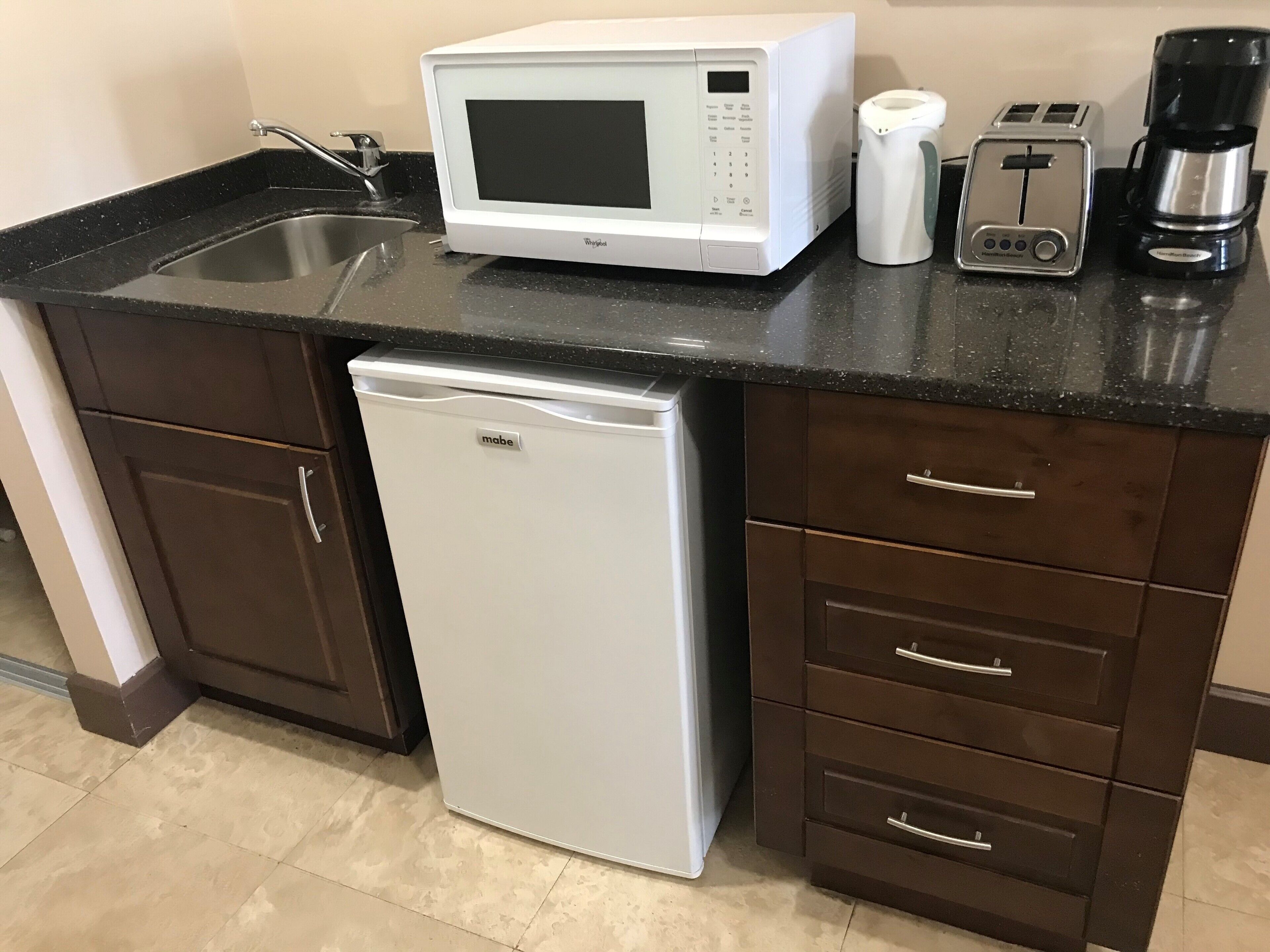 A compact kitchen with a microwave, toaster, coffee maker, and dishwasher.