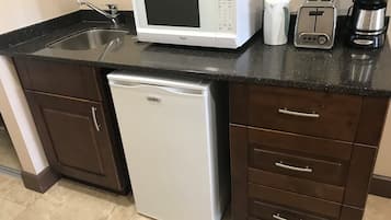 A compact kitchen with a microwave, toaster, coffee maker, and dishwasher.