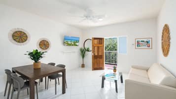 Una sala de estar moderna con comedor, ventilador de techo y vistas a través de una puerta.
