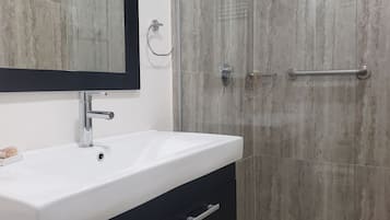 Uma casa de banho moderna com uma pia branca, um espelho e um chuveiro com porta de vidro.