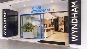 Exterior de un hotel Club Wyndham con diseño moderno, que presenta una entrada destacada, una recepción y una planta grande en maceta.