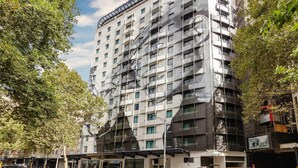 Un hotel de varios pisos con un diseño arquitectónico moderno, que cuenta con balcones y una entrada destacada.