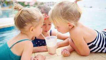 Children enjoy a poolside conversation in an outdoor setting.