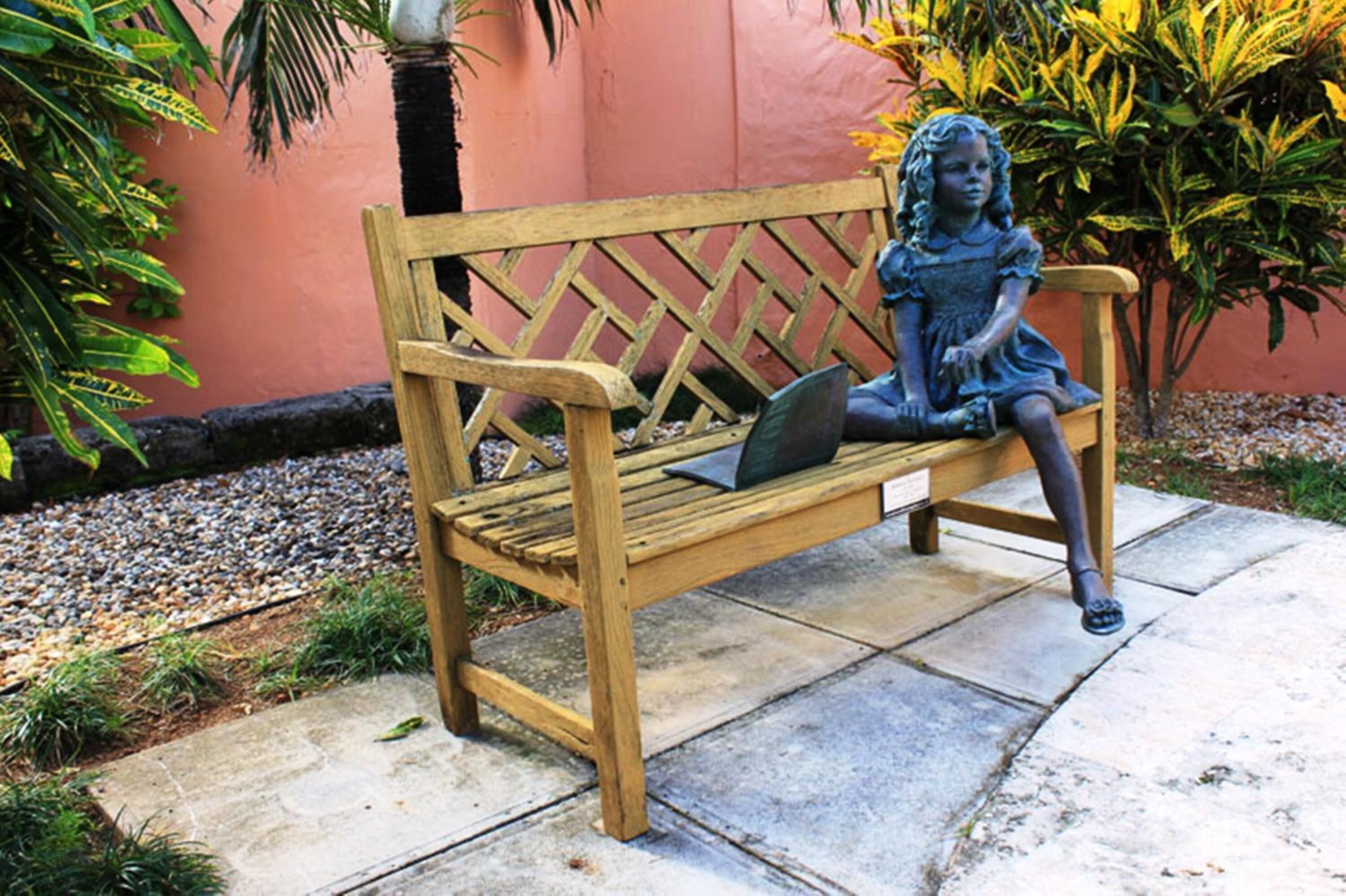 A wooden bench with a statue of a child.