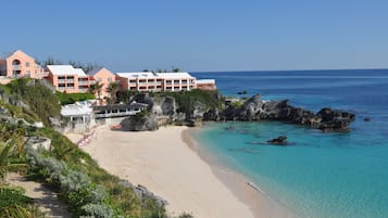 A beachfront hotel with multiple buildings, a sandy beach, and clear blue waters.
