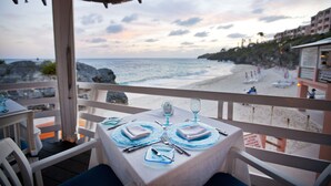 A table set for two with a view of the beach and ocean.