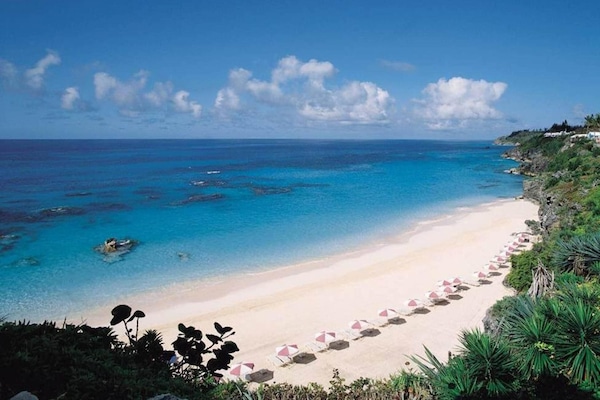 En la playa, arena blanca, sillas reclinables de playa, sombrillas
