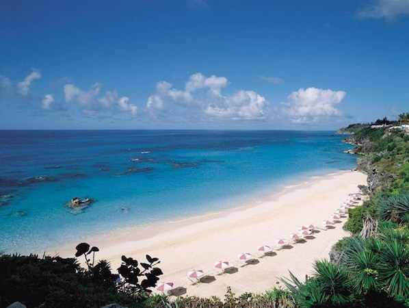 En la playa, playa de arena blanca, camastros y sombrillas 