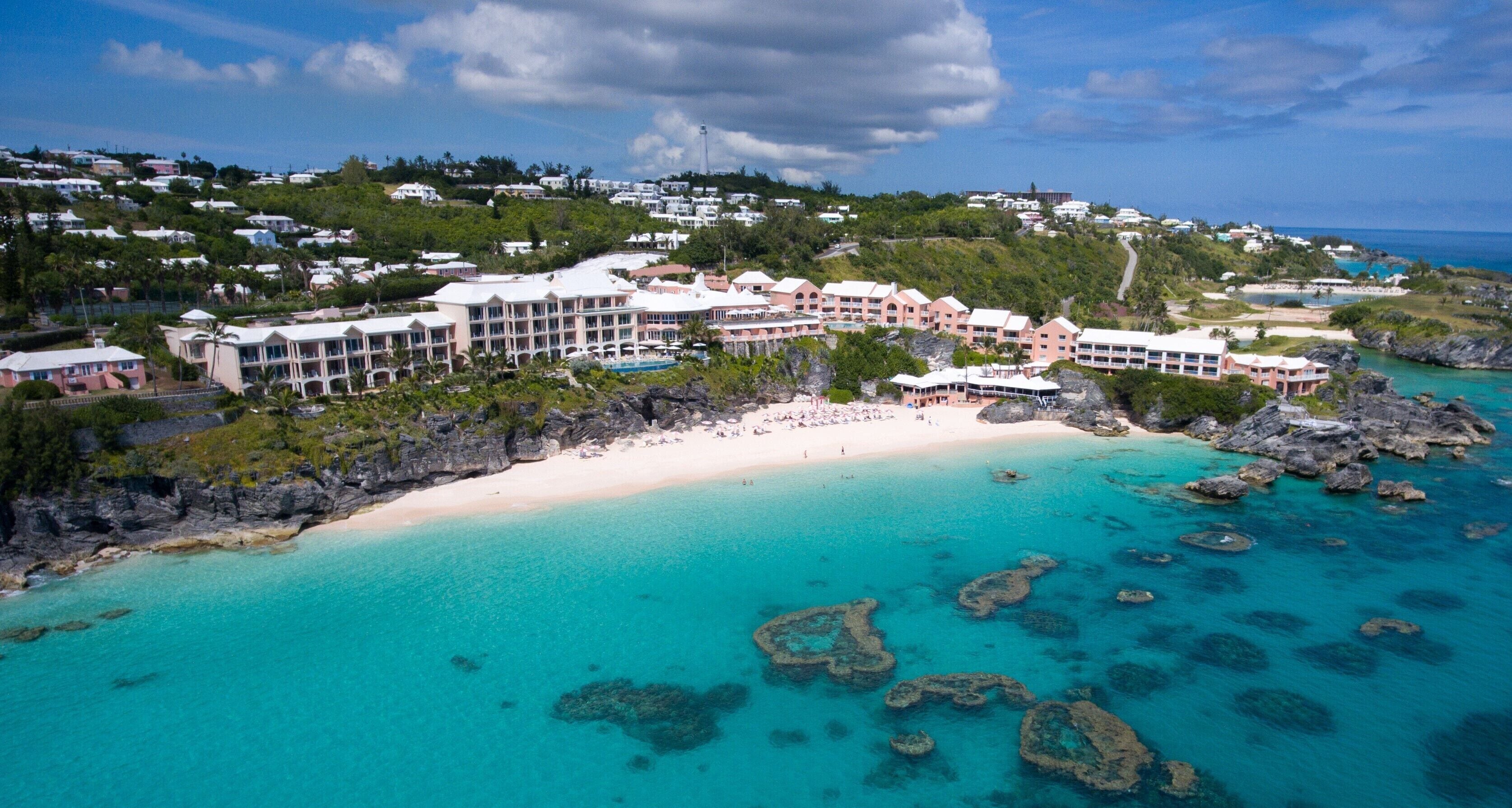 Un resort con varias construcciones, una playa y aguas turquesas cristalinas.
