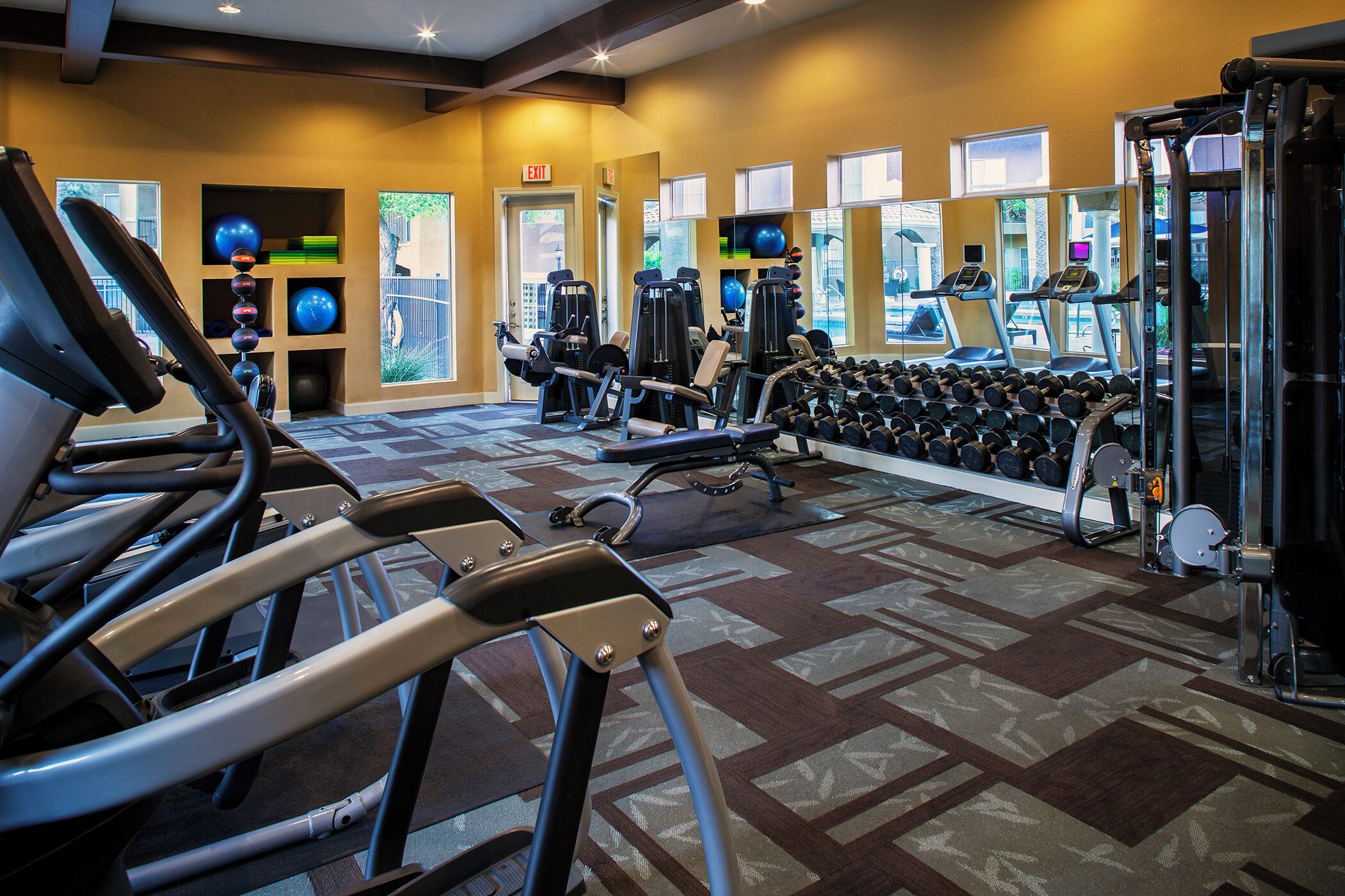 Ein Fitnessstudio mit Laufbändern, Kraftgeräten und verschiedenen Kurzhanteln.