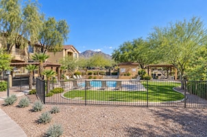 A residential area with a swimming pool, fenced yard, and mountain views.