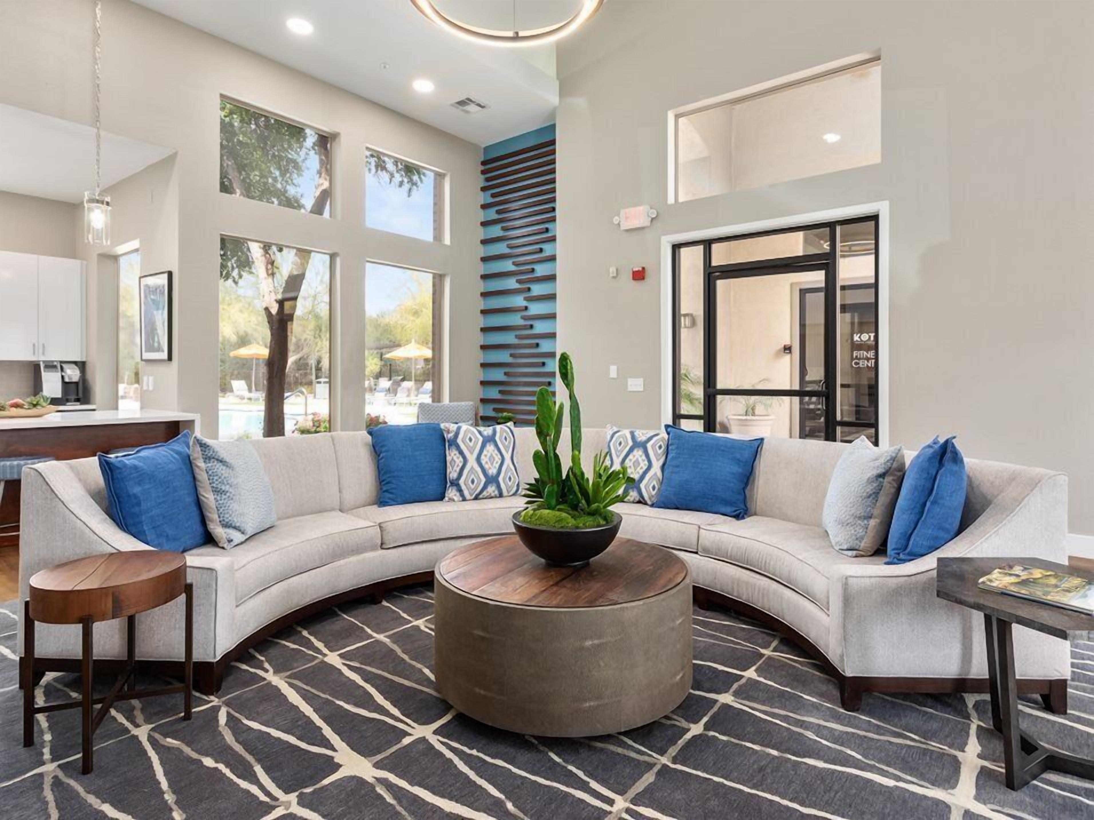 A modern lobby with a curved sofa, a round coffee table, and a patterned rug.